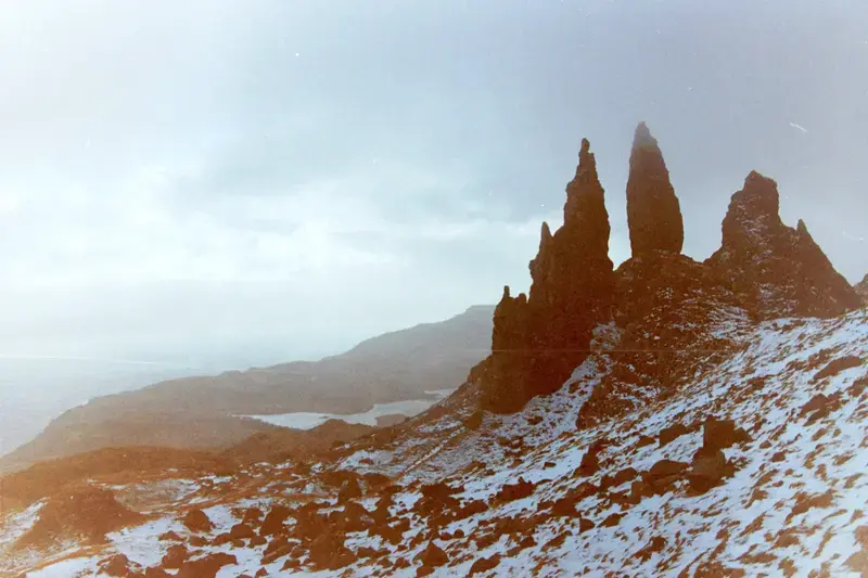 Dark rock pinnacles rising above snow and a misty valley.