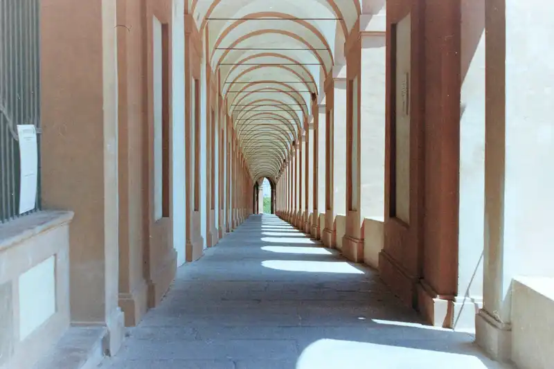 A long covered arcade with repeating arches and columns.
