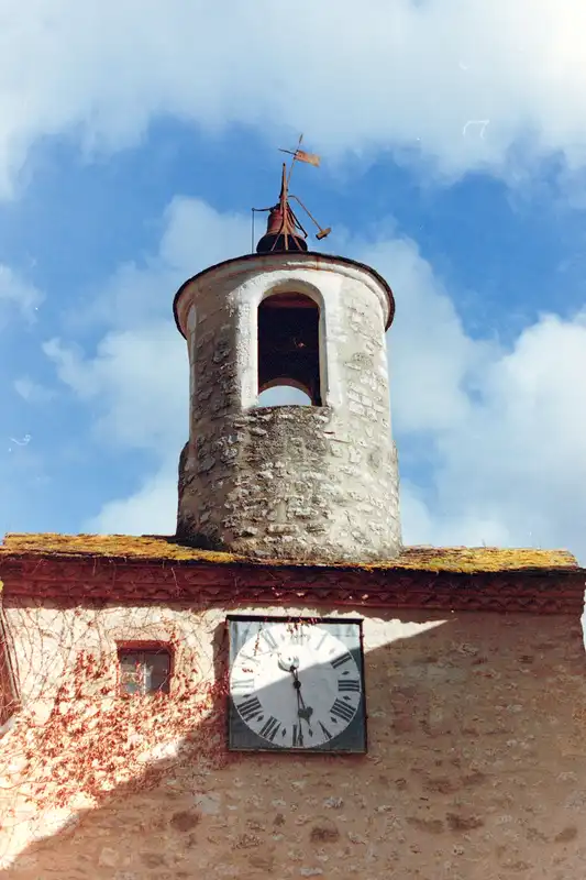 A stone clock tower with an open belfry against a blue sky.