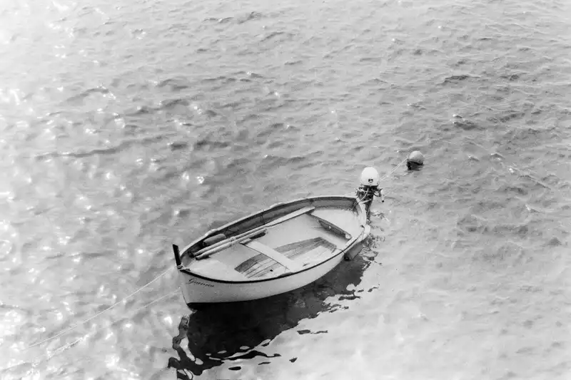 A small rowboat floating in shallow water, photographed in black and white.