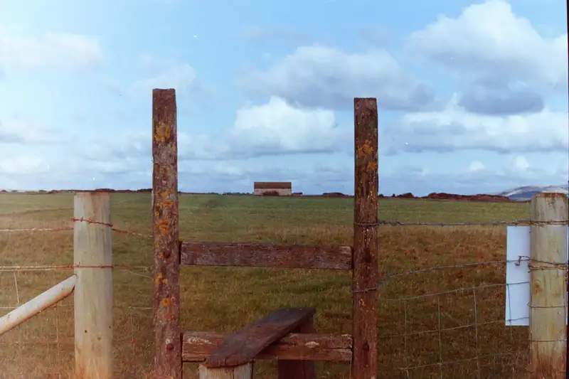 A weathered wooden stile in a field beneath a cloud-filled sky.